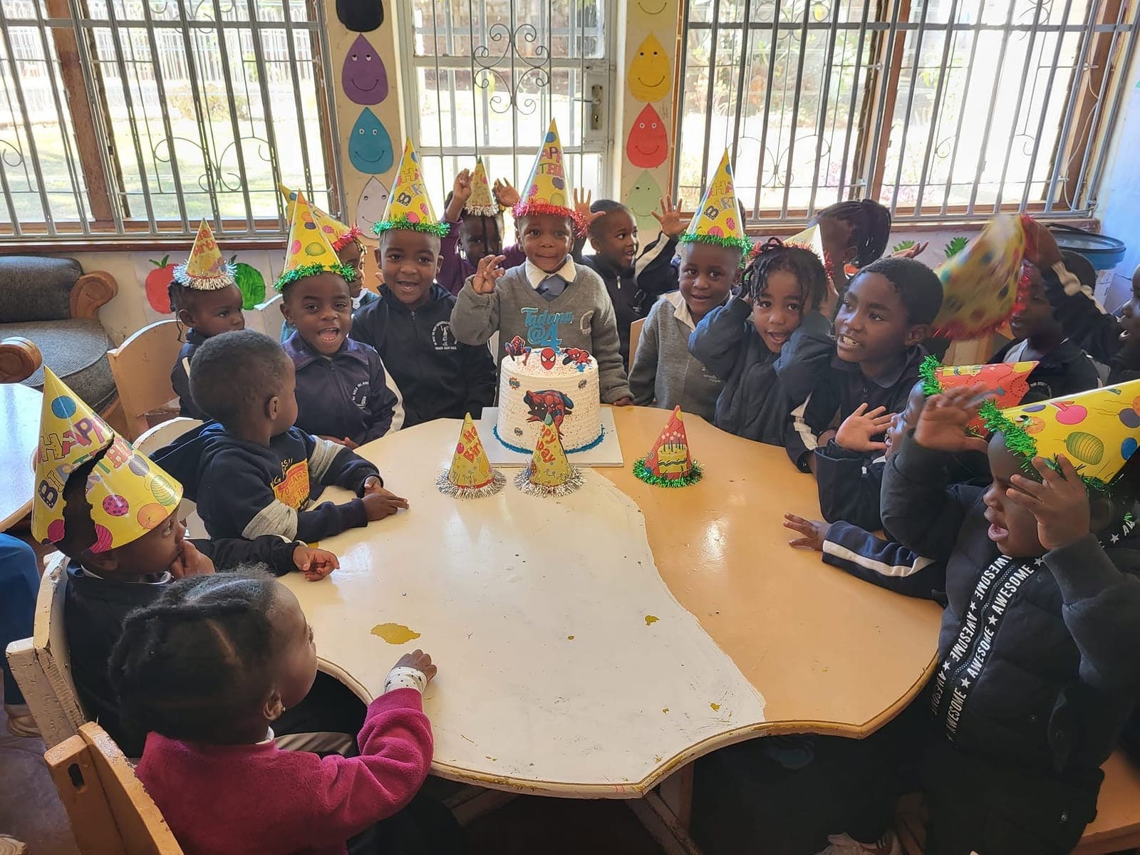 Children in party hats around a birthday cake at Nirmeen Nursery & Junior School, Harare