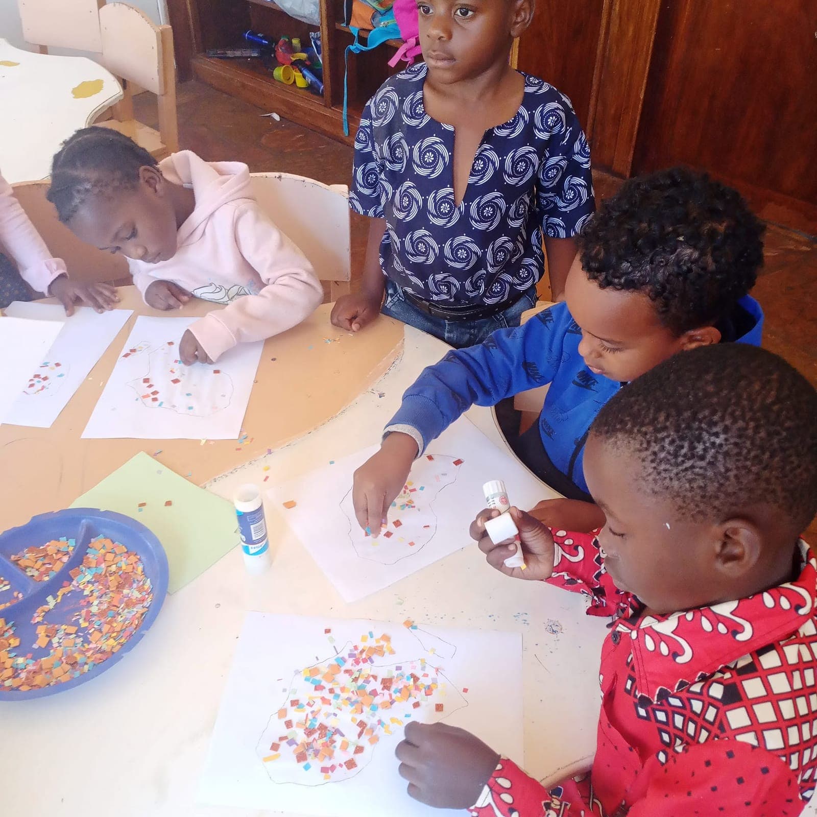 Children gluing coloured paper onto their pictures during an art lesson at Nirmeen