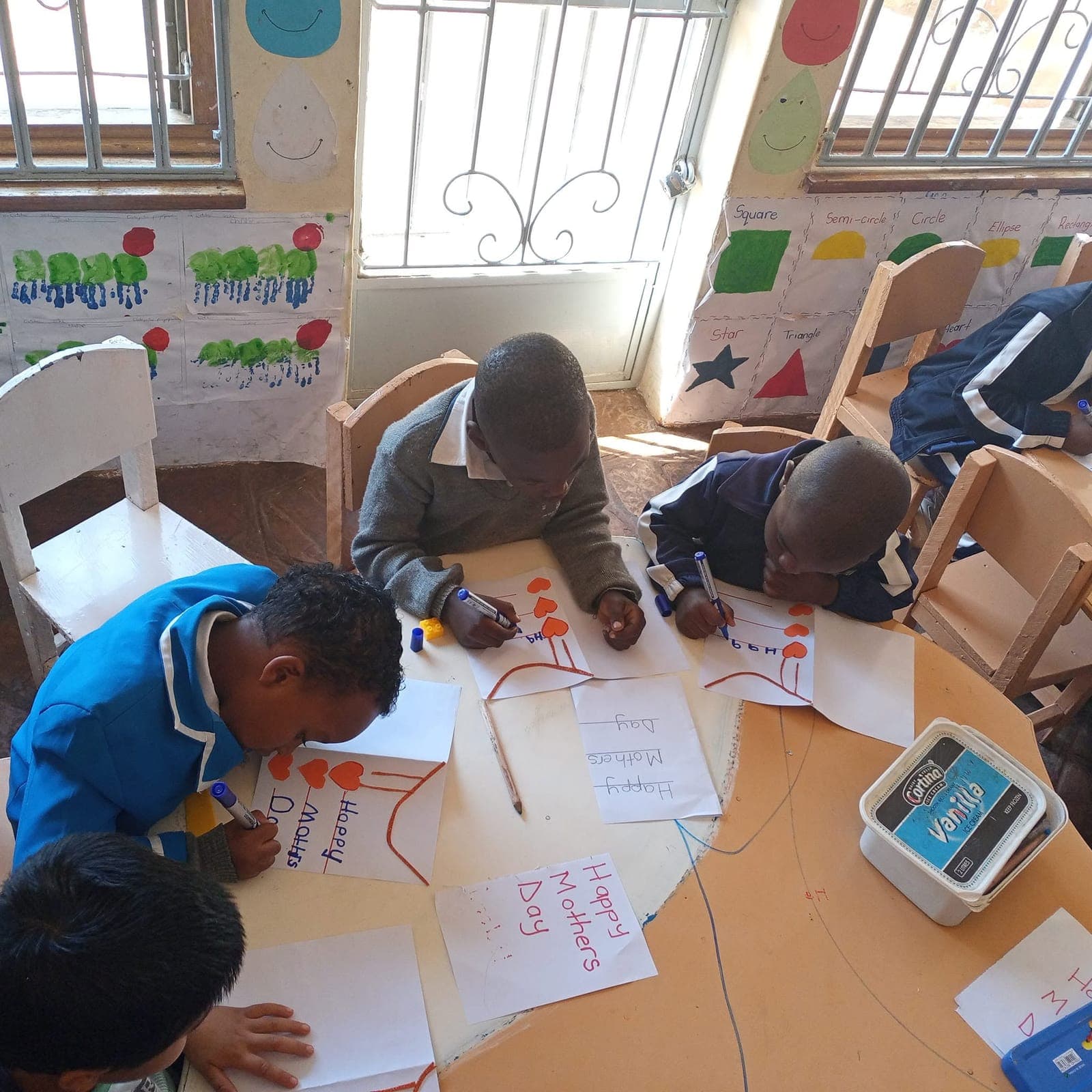 Children drawing and colouring at a classroom table at Nirmeen, Belvedere
