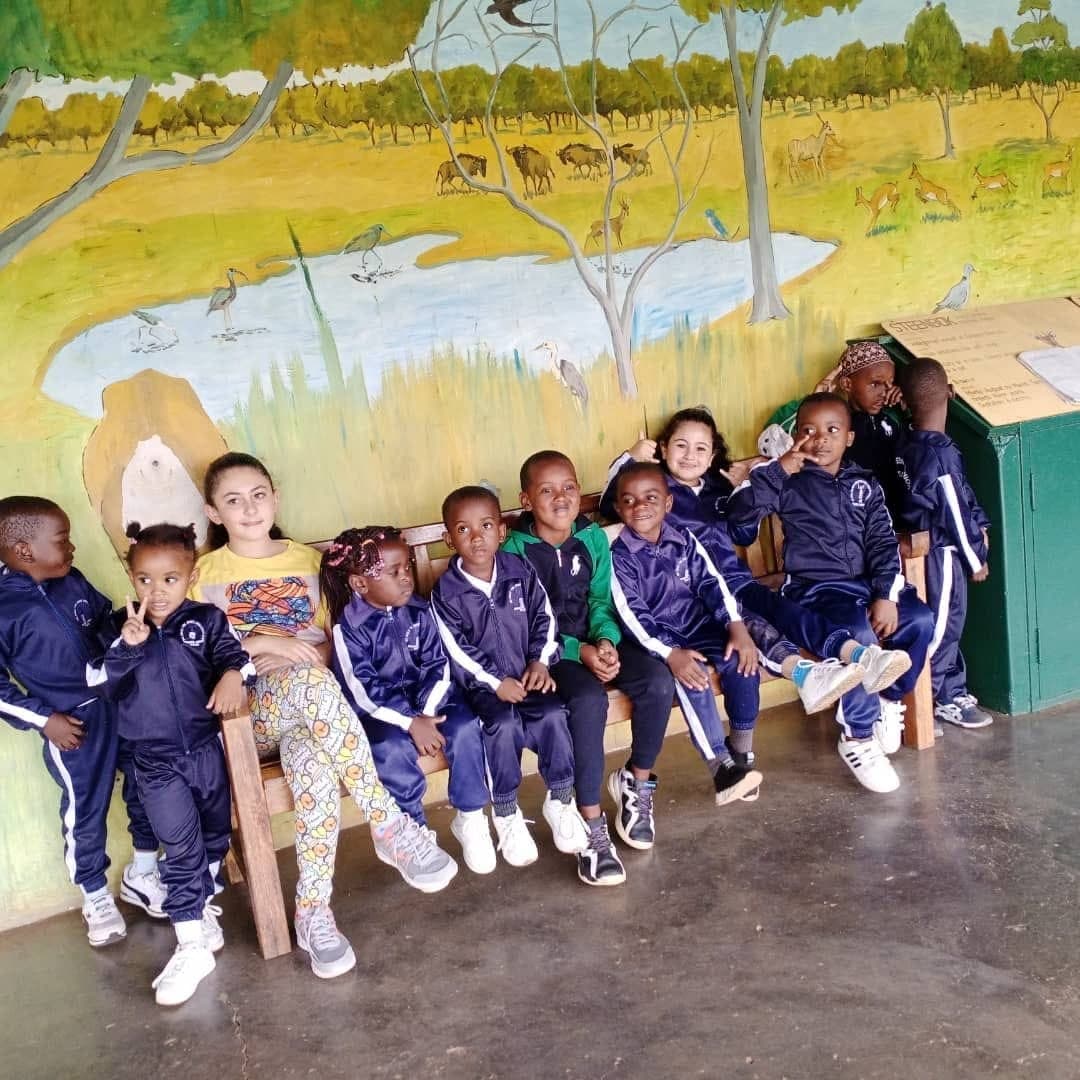 Children in school tracksuits sitting in front of a painted mural at Nirmeen, Belvedere