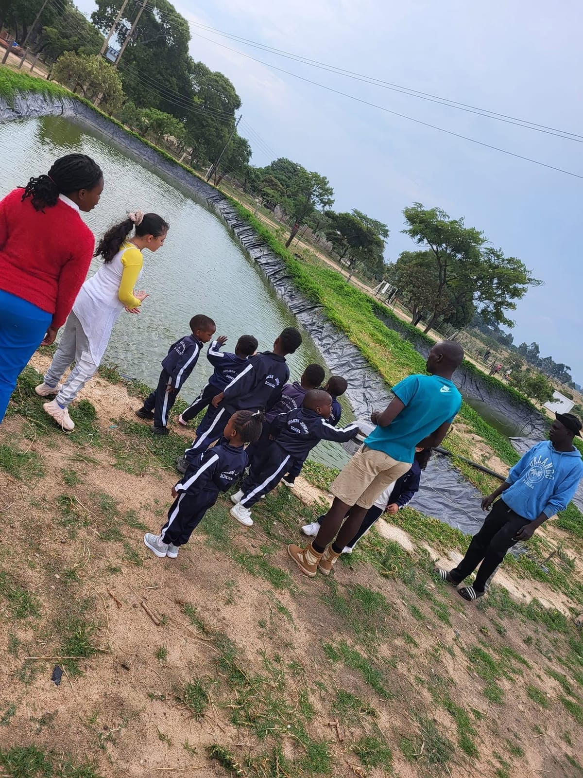 Children and teachers on an outdoor nature walk beside a stream with Nirmeen Nursery & Junior School